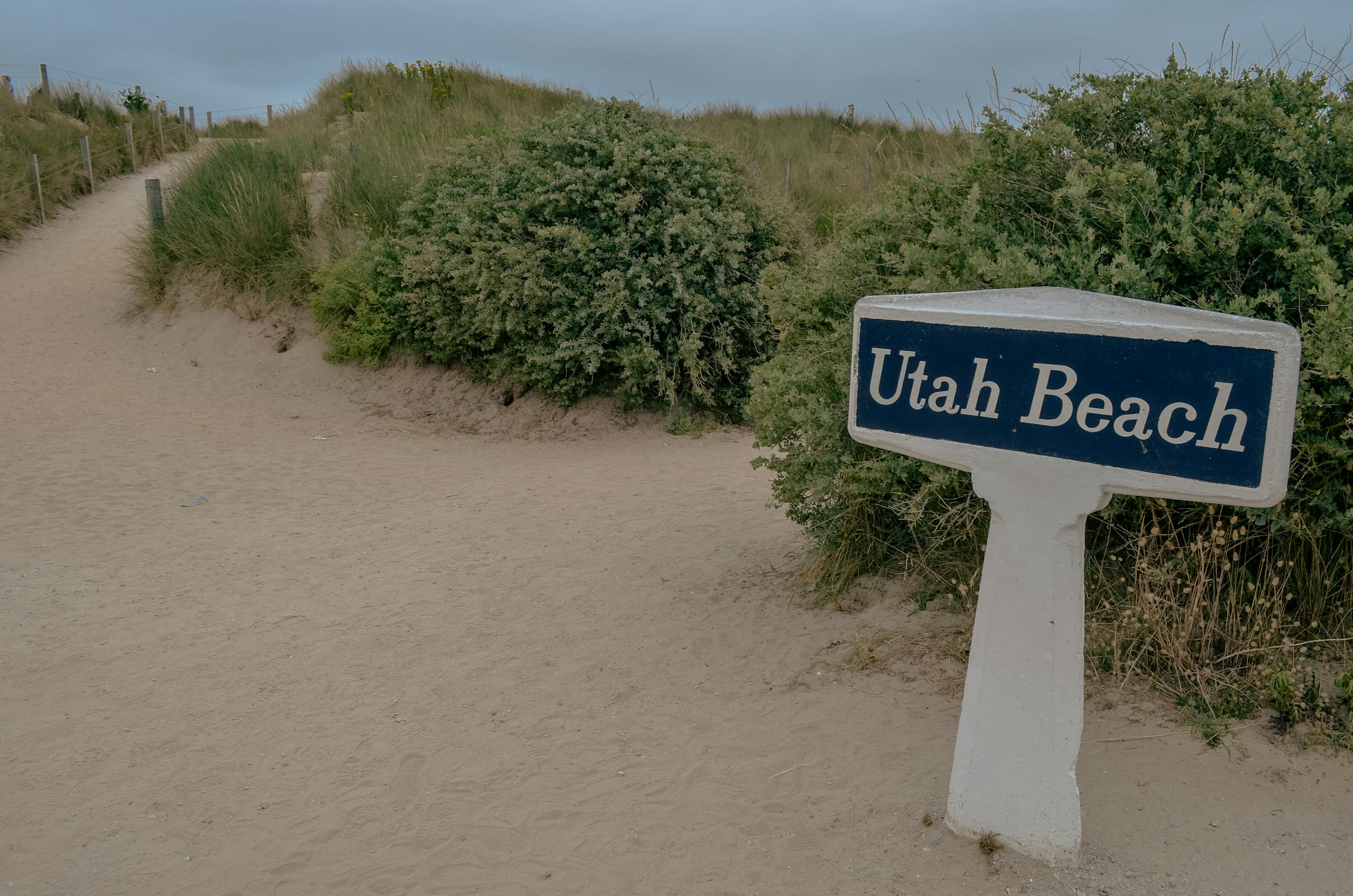 Pathway leading to Utah Beach in Normandy, marked by a distinct sign, famous for WWII history.